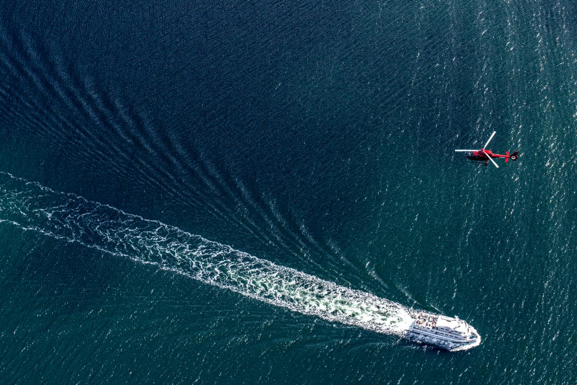 Rügen-Helikopter im Flug über Fährschiff bei Rügen