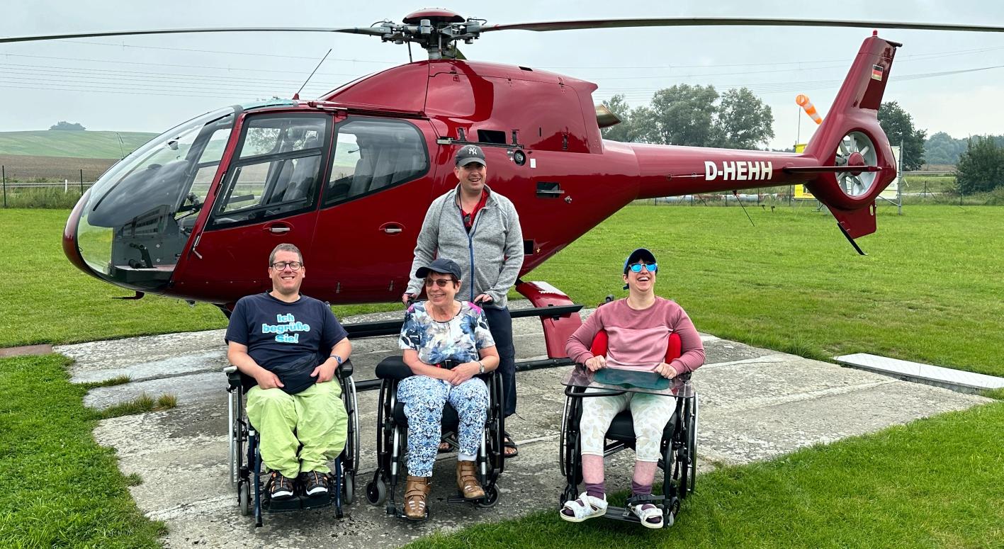 Gruppe von Rollstuhlfahrern vor dem Helikopter von Rügen-Helikopter